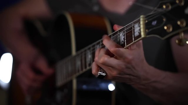 Playing acoustic guitar side angle close up strumming left hand in focus left hand 