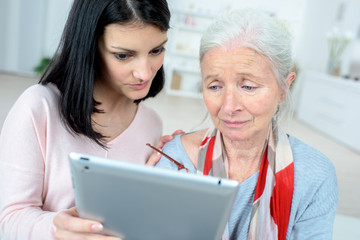helping old woman use a tablet computer