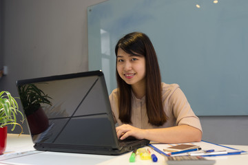 Smiling Asian office lady in workplace