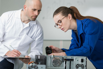 man looking for woman trainee fixing computer at work
