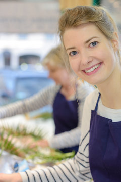 portrait of cheerful female shop assistant selling fresh fish