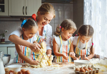 Happy family mother and children twins   bake kneading dough in kitchen