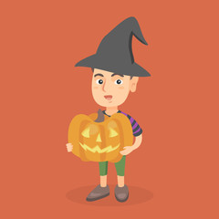 Young caucasian boy in a black witch hat holding a carved pumpkin for Halloween in hands