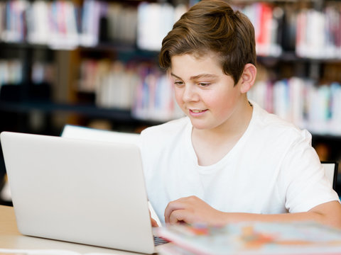 Teenage boy with tablet in library