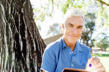 Senior man sittingin park while reading book