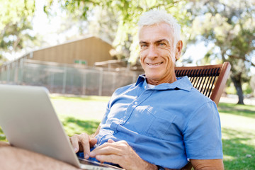 Senior man with notebook sitting in the park