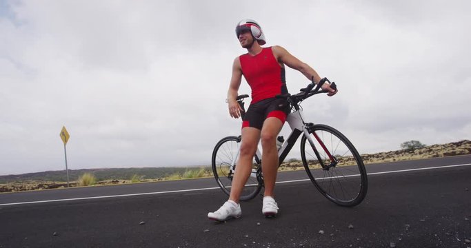 Male triathlete portrait with triathlon bike - Triathlon cycling. Fit cyclist man on professional triathlon bicycle wearing time trail helmet for ironman race. From Big Island Hawaii. SLOW MOTION.