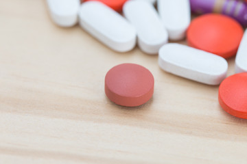 Obraz na płótnie Canvas White, black and red medicine pills on a wooden background.