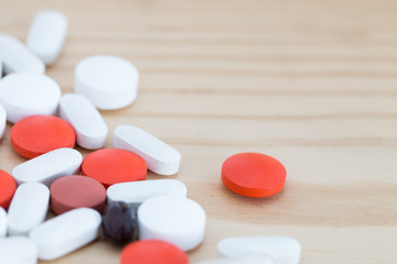 Fototapeta na wymiar White, black and red medicine pills on a wooden background.