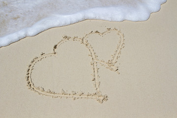 Heart drawn on a sand of beach with the wave of the sea in the morning with place for your text. Summer holiday concept. Romantic love background. Valentine's Day theme. Top view. Copy space.