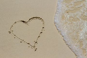 Heart drawn in the sand. Beach background. Top view
