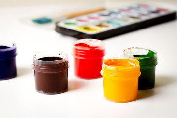 Painting, drawing, art background. Colorful gouache and paints on white table
