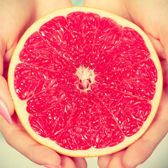 Half of red grapefruit citrus fruit in human hands