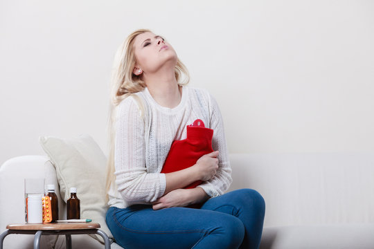 Woman feeling stomach cramps sitting on cofa