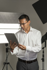 Fototapeta na wymiar Man in Business Suit Staring at Tablet Computer in Studio
