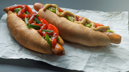 Tasty hot dogs on paper on grey background