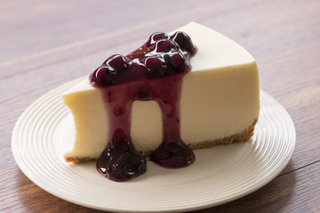 Blueberry cream cheesecake in white plate on wood table