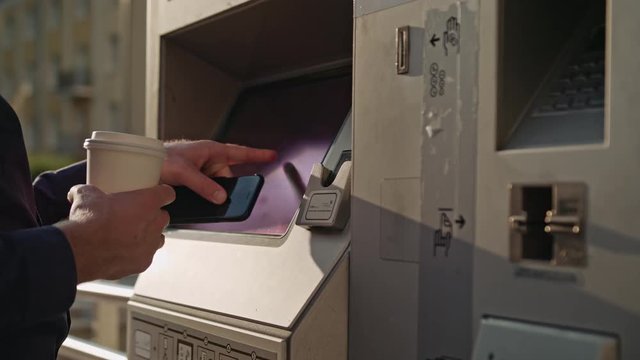 A young man using an ATM. Close-up shot