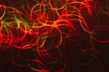 Abstract background of colorful lines in motion on black. Bokeh of defocused curves, blurred neon red, green and yellow leds, festive backdrop of serpantine, holidays and celebrations