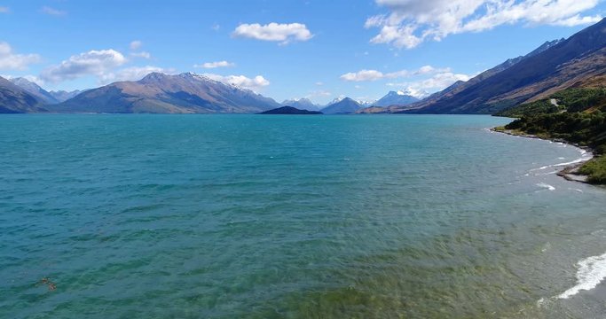 Tourist hiking in New Zealand by lake - aerial drone video nature landscape on South Island, lake Wakatipu and southern alps between Queenstown and Glenorchy. New Zealand travel tourist destinations.
