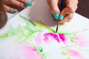 Close-up of the artist draws watercolor in the album for drawing with a thin wooden brush, on the...