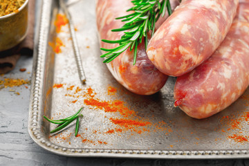 Close up raw sausages for grilling on tray with rosemary