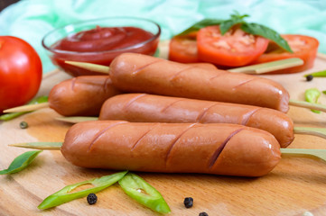 Sausages on skewers with ketchup and fresh tomatoes, served on a round wooden tray. Snack to beer. Oktoberfest.