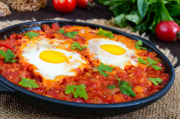 Shakshuka - a dish of eggs fried in a sauce of tomatoes, hot pepper, onions and seasonings. Israeli cuisine. Served for breakfast with rye bread.