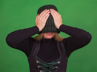 Young woman covers her face with a knitted hat