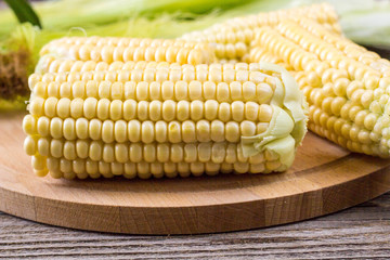 Fresh corn on cobs on rustic wooden table, closeup
