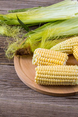 Fresh corn on cobs on rustic wooden table, closeup