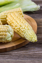 Fresh corn on cobs on rustic wooden table, closeup