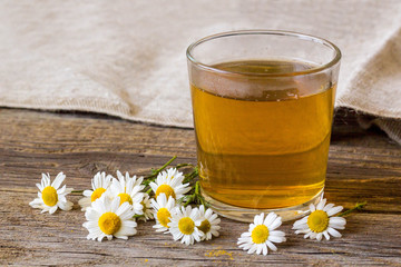 Cup of tea with chamomile flowers on rustic wooden background