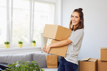 Young woman moving into new apartment holding cardboard boxes with belongings