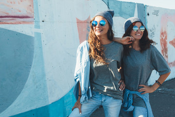 Models wearing plain tshirt and sunglasses posing over street wall