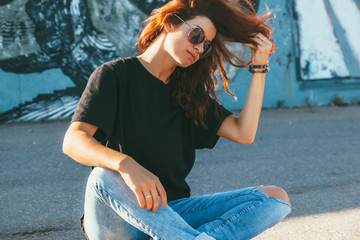 Model wearing plain tshirt and sunglasses posing over street wall - obrazy, fototapety, plakaty