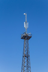 Metal tower with antennas for mobile cell phone communications against blue sky