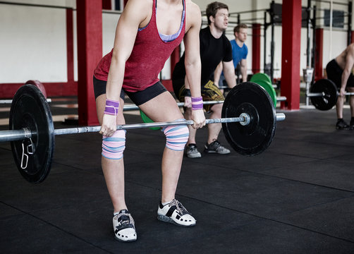 Low Section Of Female Trainer Lifting Barbell