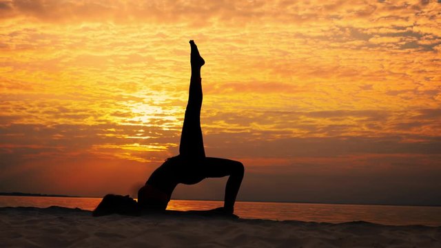 Woman practicing yoga, yoga asana in slowmotion at sunrise