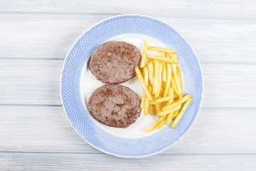 Hamburger with french fries on blue plate on wooden table. Food.