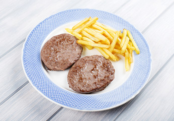 Hamburger with french fries on blue plate on wooden table. Food.