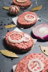 Organic fresh minced meat cutlets. Raw Ground beef meat Burger steak with ingredients on grey background