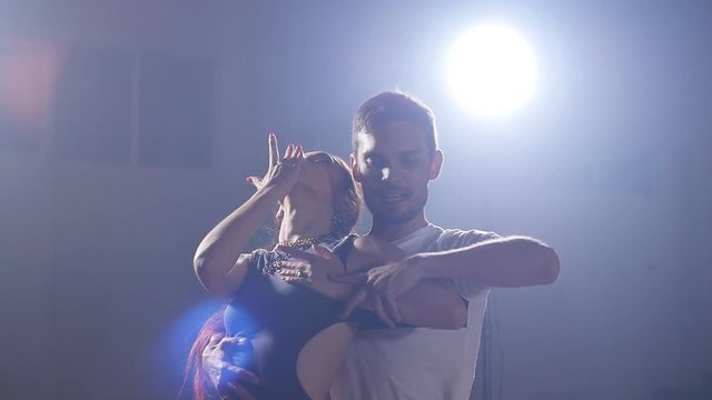 Young couple dancing latin music. Bachata, merengue, salsa. Dark room
