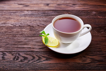 Cup with green tea and teapot on wooden background
