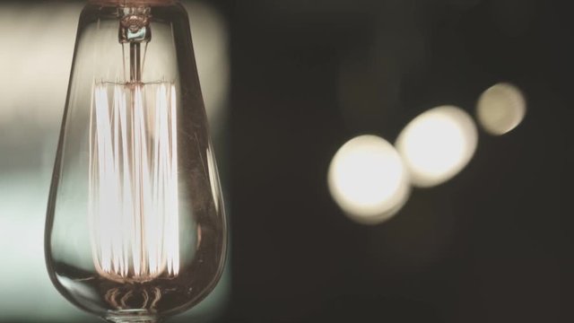 Vintage lamp light. Classic edison light bulb in room. Close up of vintage lightbulb indoors. Decorative antique style light bulb on dark background. Antique lightbulb