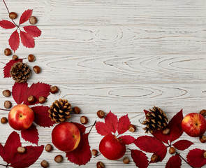 Autumn red leaves with apples on a wooden background.