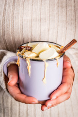 Autumn, winter drinks. Ideas for Christmas, Thanksgiving, Halloween. Girl drink hot spicy pumpkin white chocolate, with marshmallow, cinnamon, anise. With knitted plaid. Copy space, hands in picture