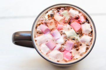 Hot chocolate mug  with colorful  marshmallow on white rustic wooden table. Winter  Christmas cozy home concept