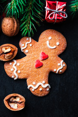 Christmas composition with Christmas gift, gingerbread man cookie, fir tree branches, xmas holiday decorations and festive symbols on dark background, flat lay