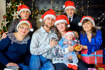 a big happy family in caps of Santaclaus celebrates Christmas, gives each other presents and has fun